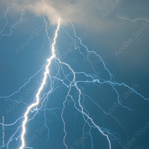 Fork lightning against blue sky on stormy summer day