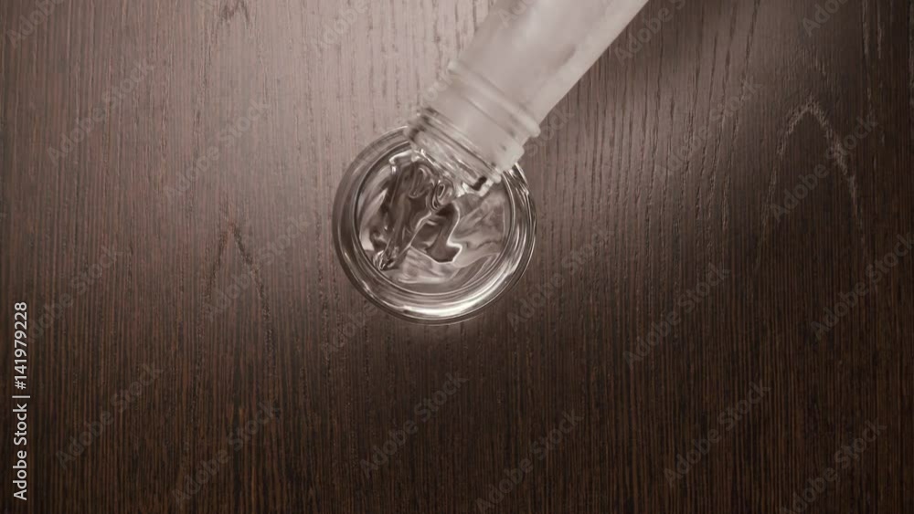 Male hand puts on the table a shot glass for vodka and pours ice-cold vodka. Top view Male hand puts on the table a shot glass for vodka and pours ice-cold vodka. Top view