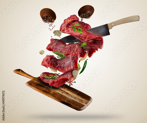 Flying raw steaks with ingredients, food preparation concept