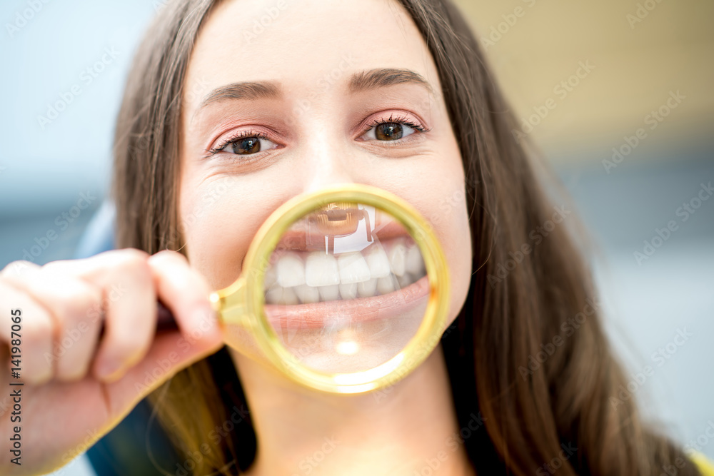 Woman smiling through the magnifying glass sitting at the dental office Woman smiling through the magnifying glass sitting at the dental office