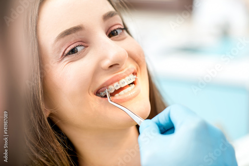 Putting dental braces to the woman's teeth at the dental office
