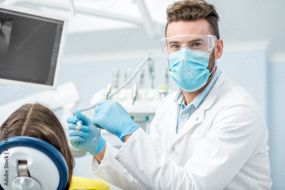 Portrait of a dentist in mask and protective glasses during the dental surgery Portrait of a dentist in mask and protective glasses during the dental surgery