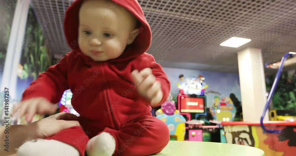 4K Cute baby sitting on a table and smiling at the children's center. 4K Cute baby sitting on a table and smiling at the children's center.