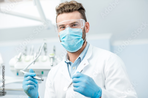 Portrait of a dentist in mask and protective glasses during the dental surgery