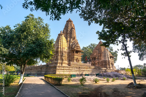Old Hindu temple, built by Chandela Rajputs, at Western site in India's Khajuraho framed by trees. photo