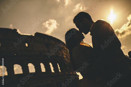 Canvas Print Young couple in love in front of the Colosseum in Rome at sunset