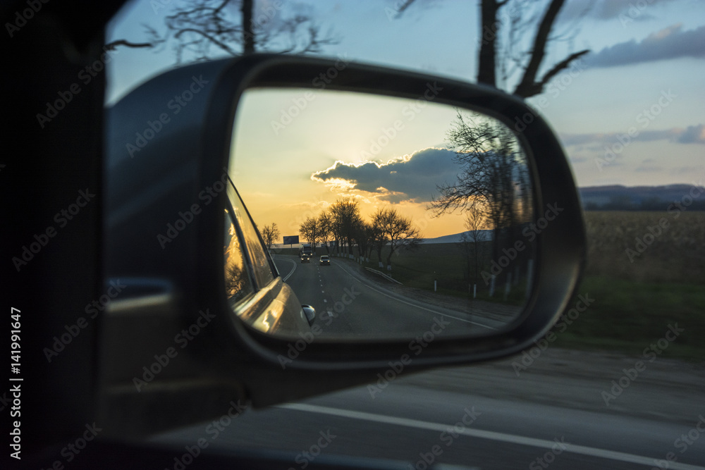 The reflection of the sunset in the automotive rearview mirror