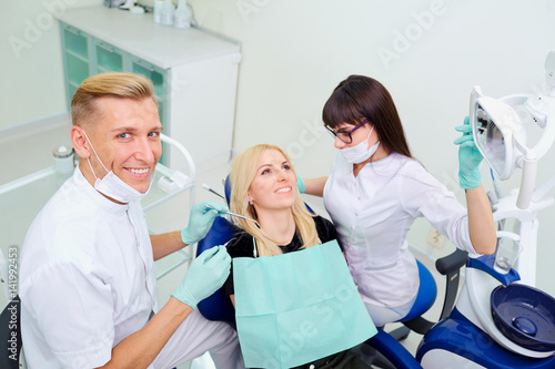 The dentist man and  assistant woman are treating  teeth to  client in dental office.