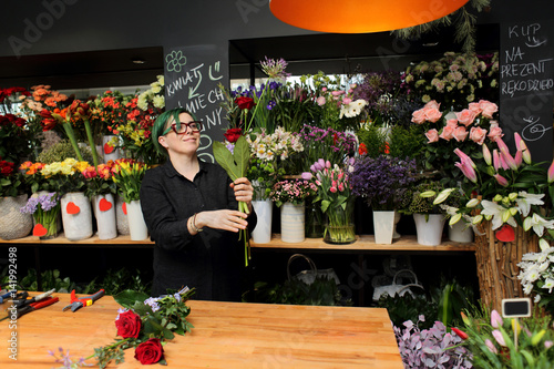 Kobieta, sprzedawca w kwiaciarni trzyma kwiaty.