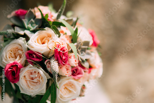 Wedding rings and bunch of roses  peonies and succulents on the stone steps. Wedding jewelry.