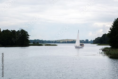 A lonely sailing boat at the lake near Trakai castle on rainy summer day, Lithuania.