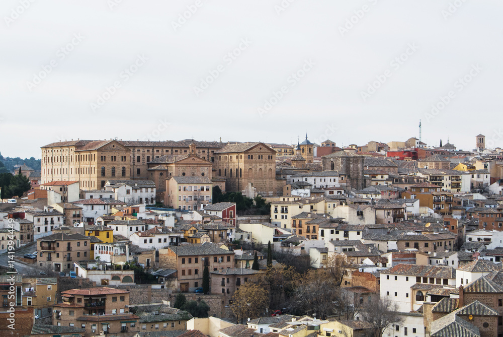 A view of Toledo old town, medieval buildings with tile roofs, churches and a building of Seminario Conciliar San Ildefonso.