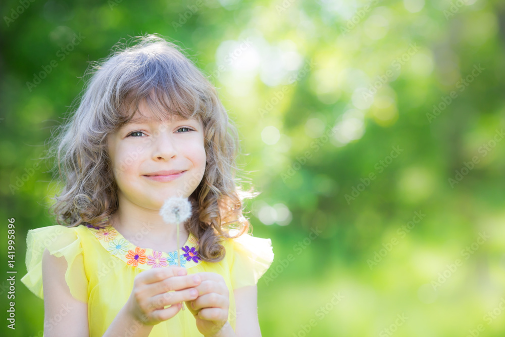 Happy child blowing dandelion flower outdoors