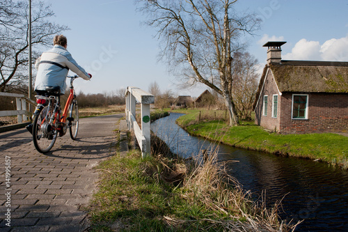Cyclist crossing bridge. Little house and wooden bridge in National Park Weerribben de wieden Netherlands. Tiny house. Kalenberg Overijssel. photo