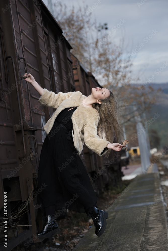 Blond young woman wear sheep jacket and black long skirt climbed on a wagon train Blond young woman wear sheep jacket and black long skirt climbed on a wagon train