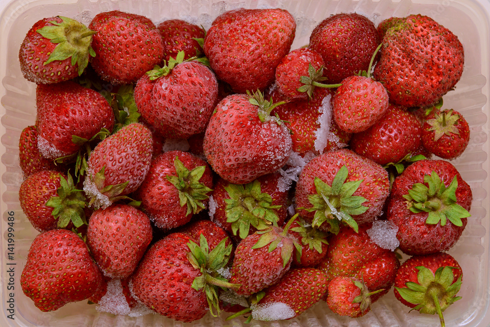 Frozen berries of red strawberries in a plastic container Frozen berries of red strawberries in a plastic container