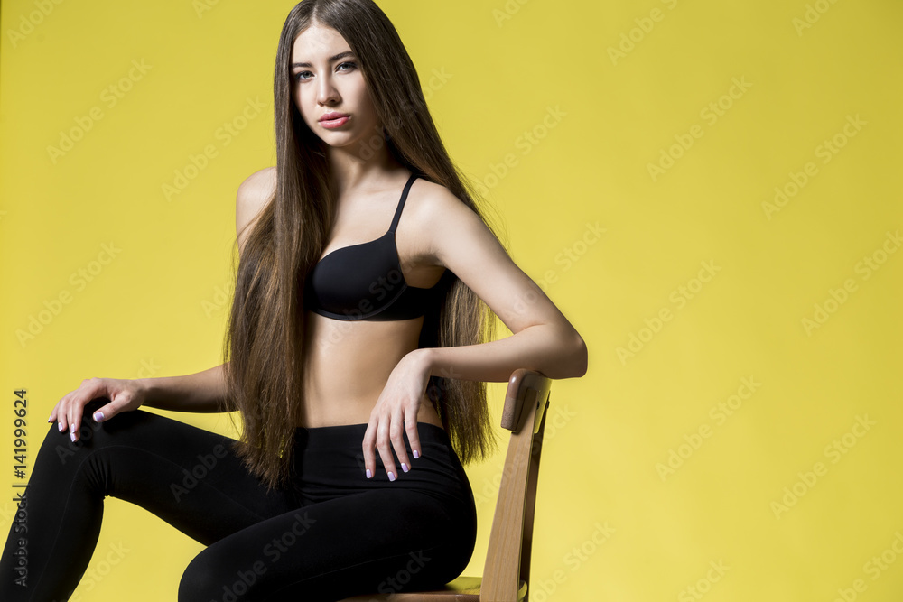 Woman in bra on a chair, yellow.