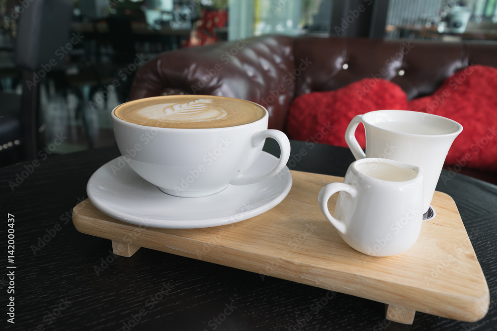 Fototapeta premium White cup of coffee on wooden table in the coffee shop.