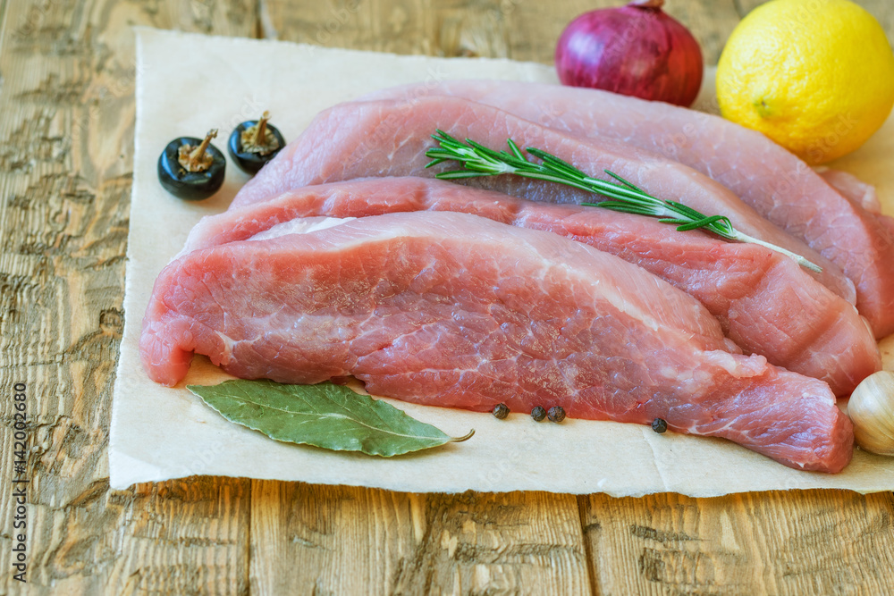 Pork with cherry tomatoes and lemon on a wooden table. Pork with cherry tomatoes and lemon on a wooden table.