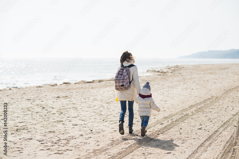 Mom and daughter are walking on the beach in winter Mom and daughter are walking on the beach in winter