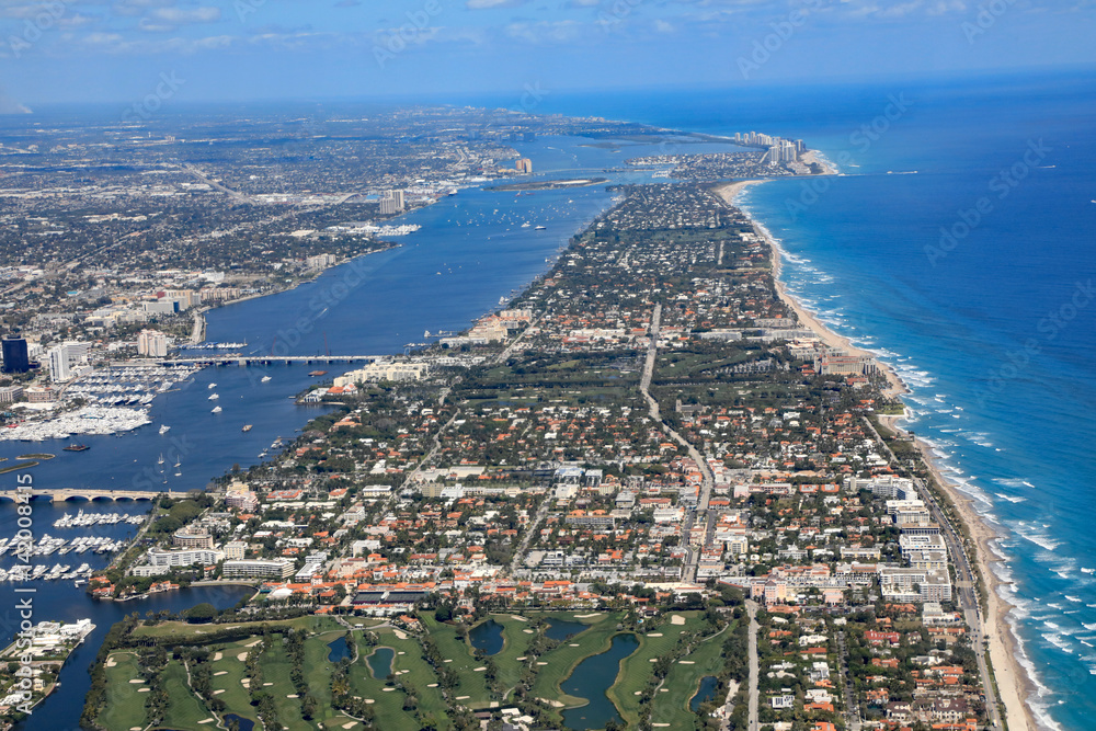 Fototapeta premium Aerial view of beautiful Palm Beach and Singer Island, Florida, along with the Atlantic Ocean, and the red roof tops of Worth Avenue.