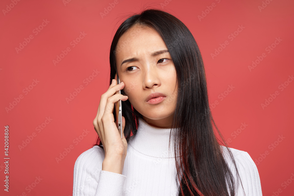 emotional brunette holding a phone in hands, red background emotional brunette holding a phone in hands, red background