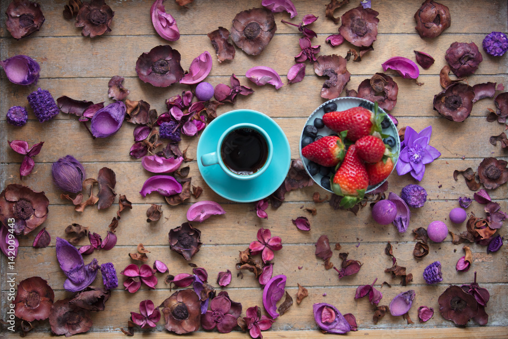 photo of cup of coffee and fresh blueberries and strawberries near wonderful dried flowers petals on the wooden background photo of cup of coffee and fresh blueberries and strawberries near wonderful dried flowers petals on the wooden background
