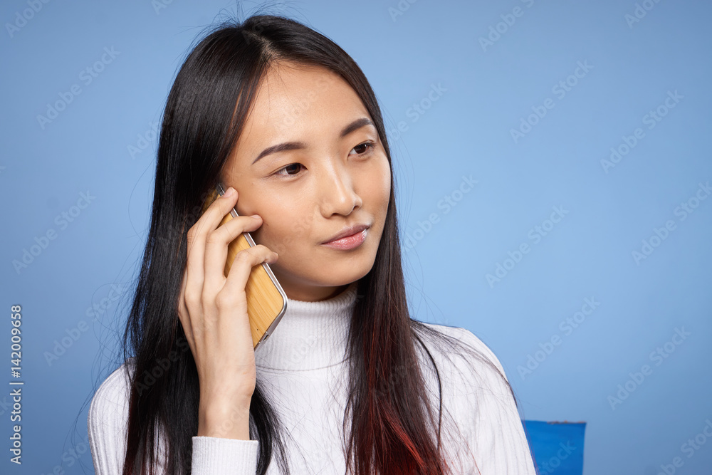woman with Asian appearance holds a mobile phone in her hand woman with Asian appearance holds a mobile phone in her hand