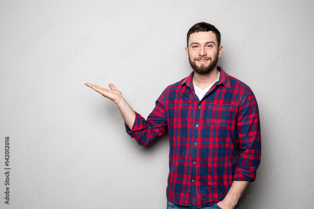 Attractive happy smiling casual young man in shirt holding copyspace on palm and showing okay gesture over gray background Attractive happy smiling casual young man in shirt holding copyspace on palm and showing okay gesture over gray background