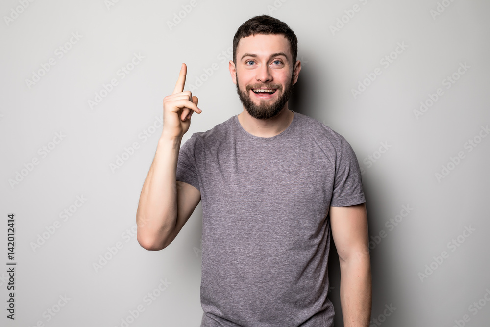 Young smiling man having a good idea isolated on white. Copy space and t shirt. Finger up. Selective focus. Young smiling man having a good idea isolated on white. Copy space and t shirt. Finger up. Selective focus.