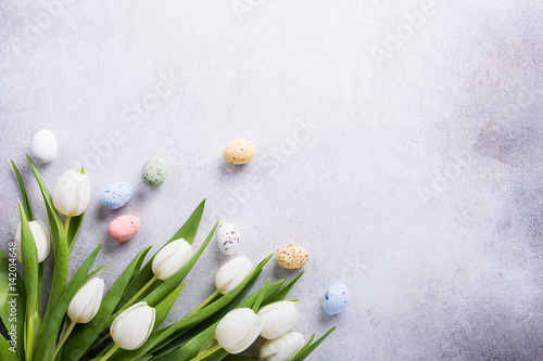 Beautiful white tulips with colorful quail eggs on light gray stone background. Spring and Easter holiday concept with copy space. #142014648