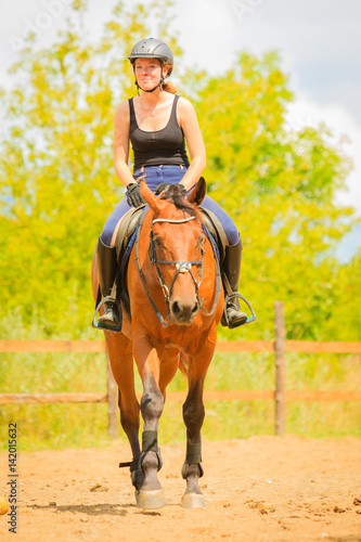 Jockey girl doing horse riding on countryside meadow