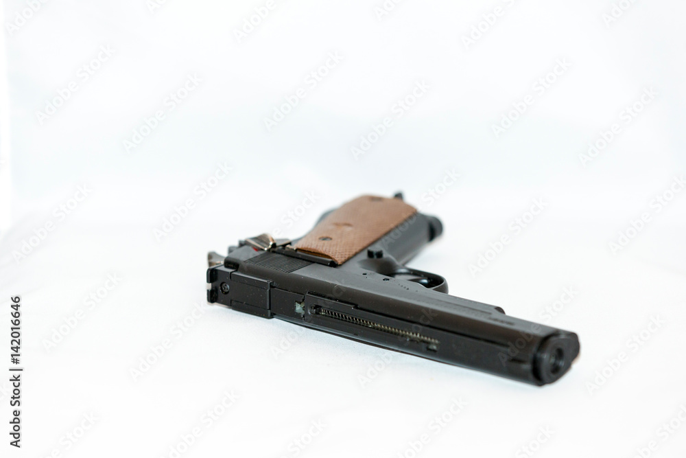 Small black handgun with a wooden handle on a white background Small black handgun with a wooden handle on a white background