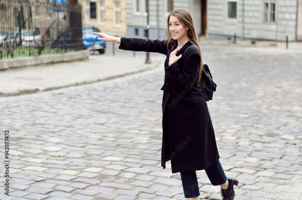 Fototapeta premium Outdoor portrait of young beautiful lady in spring, she is calling taxi