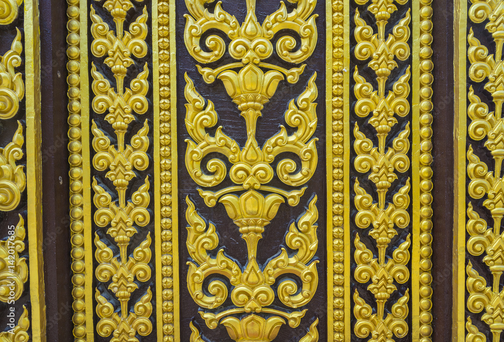 Temple door decorated with gold leaf designs Thailand