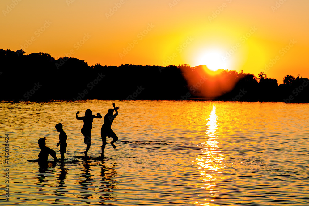 People are having fun in a lake under sunset