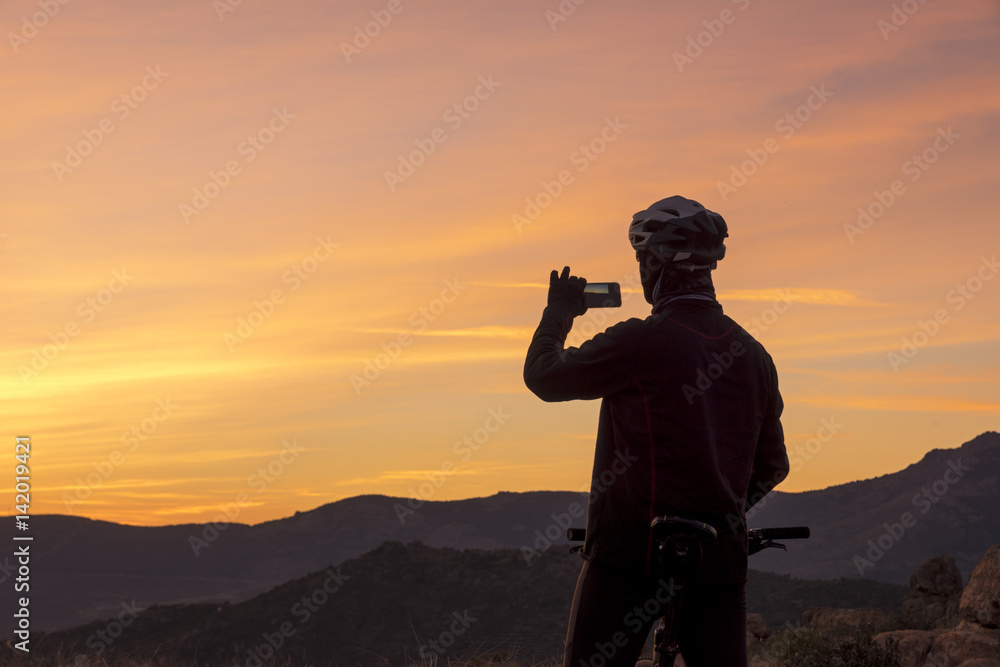 Man taking sunset sky picture on the mountain at sunset
