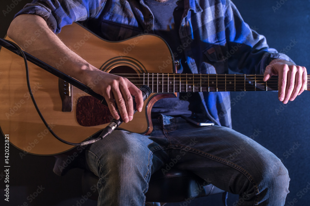 Obraz premium man playing acoustic guitar on a black background, the music concept, beautiful lighting on the stage