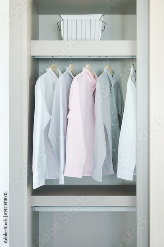 Pastel shirts hanging in wardrobe