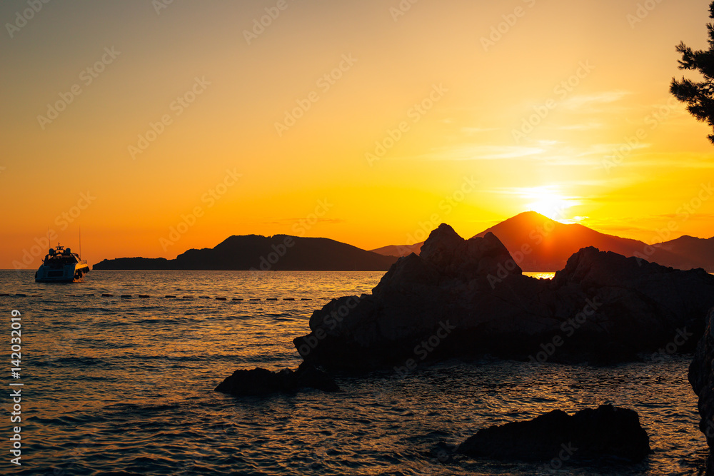 Yacht in the sea at sunset. Silhouette of a yacht on the background of the setting sun on the horizon