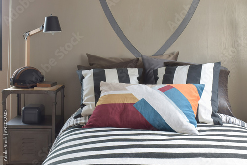 Wooden reading lamp on bedside table next to Striped bedding style in the bed room