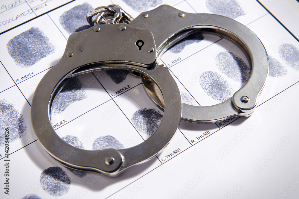 Handcuffs laying on top of fingerprint chart Stock Photo | Adobe Stock