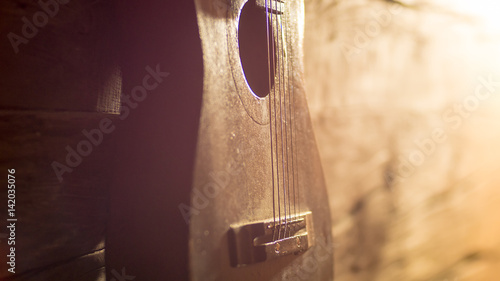 Acoustic guitar leaning on grungy wooden wall