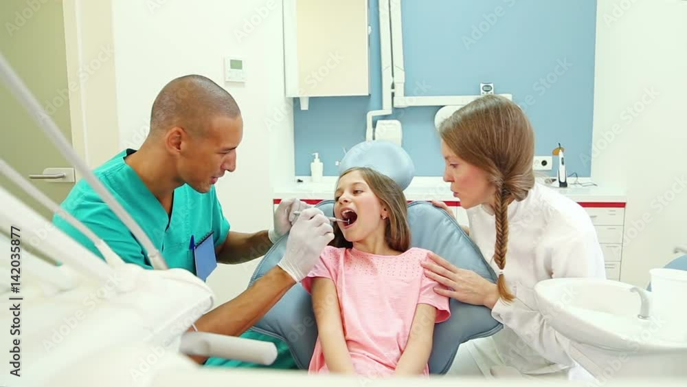male dental surgeon and cute little girl high five after dental check up male dental surgeon and cute little girl high five after dental check up
