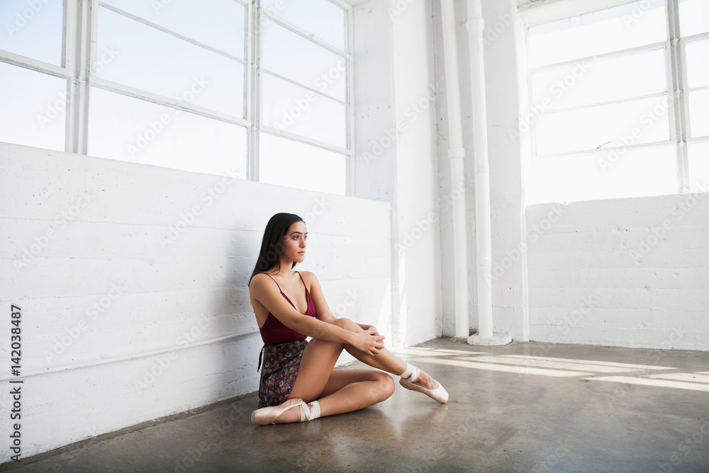 Fototapeta premium Sexy beautiful ballerina in pointe shoes is sitting in a dance studio