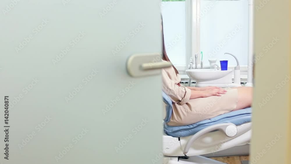Beautiful brunette female patient greeting dentist while sitting on dental chair Beautiful brunette female patient greeting dentist while sitting on dental chair