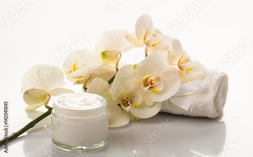Moisturizing cream and orchid on white background