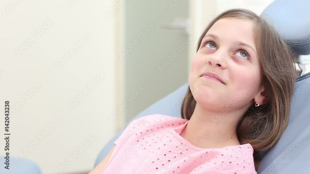 Cute little girl smiling and talking with dentist while sitting in the dental chair Cute little girl smiling and talking with dentist while sitting in the dental chair