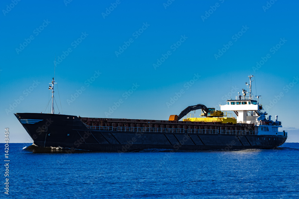 Obraz premium Black cargo ship with long reach excavator moving by baltic sea