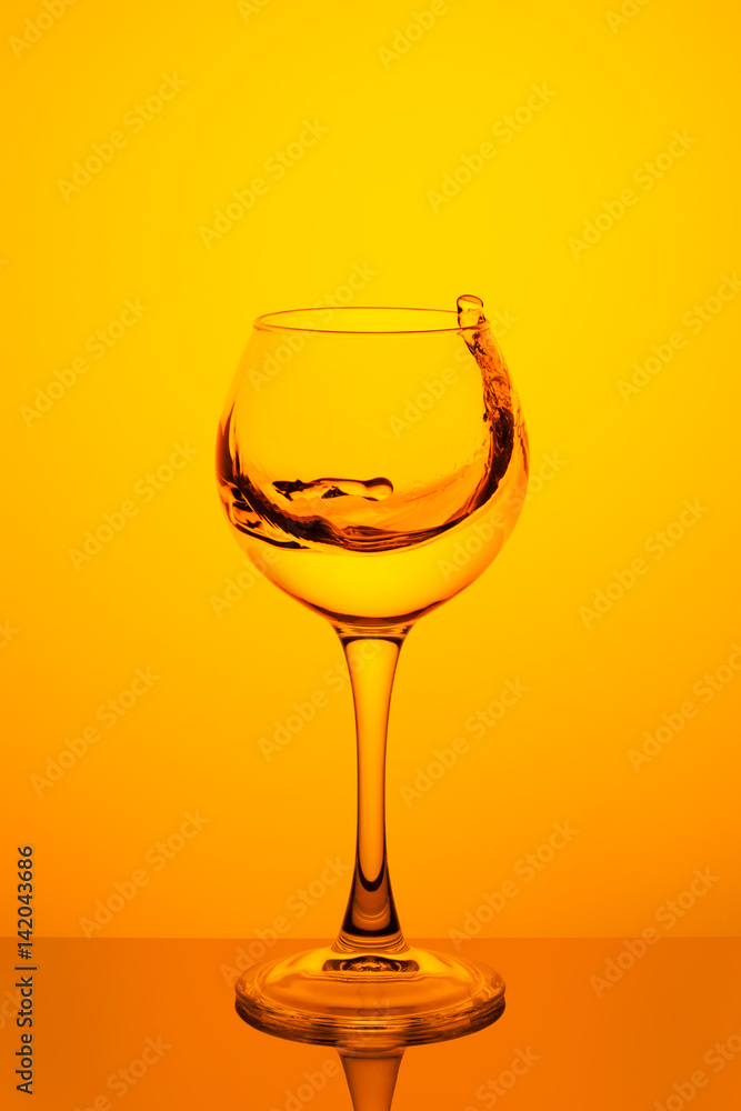 Splash of water in a glass on yellow Splash of water in a glass on yellow